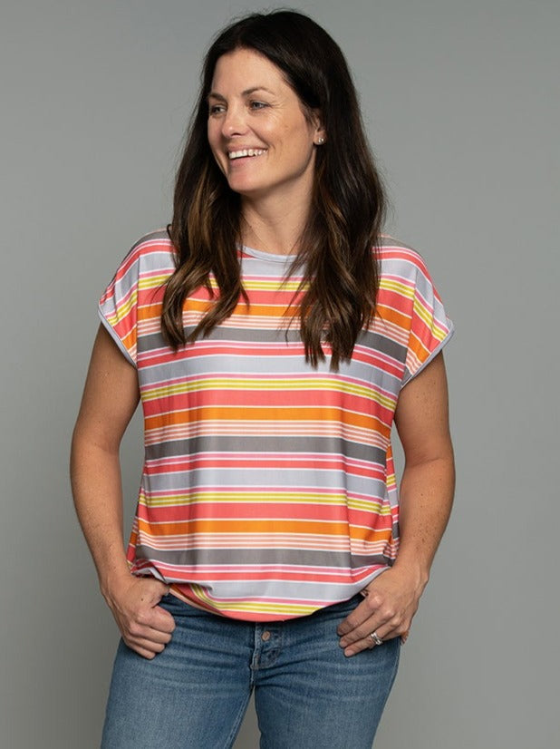 Flip Outfit Reversible Women’s Relaxed T Shirt, Top - multicolor pink, orange, and grey stripe print reverses to oversized pink dots on grey background. Loose fit sweat-wicking UPF 50. Made in the USA from recycled plastic bottles. Made by women for women. Front view of multicolor stripes side.
